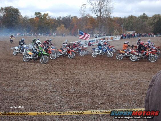 Motocross race start with multiple dirt bikes and riders on a dirt track