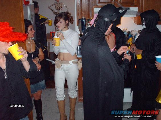 People in Halloween costumes holding drinks at a party. Date stamp reads 03/20/2005