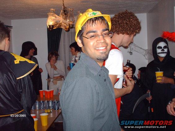 People in Halloween costumes at a party, with drinks and cans on a table
