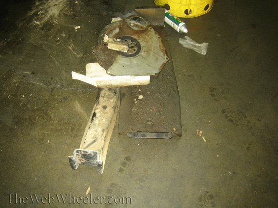 Rusty engine bell housing and bracket on a dirty floor
