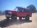 1996 Ford Bronco - This red Ford Bronco is kicking up sand as it drives through a sandy terrain.