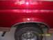 1994 Ford Bronco - Close-up of a red vehicle's rear fender showing damage and a tire.