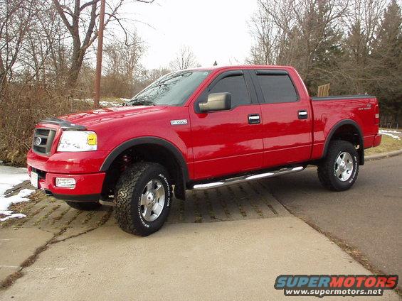 Red Ford F-150 pickup truck parked on a concrete surface with trees in the background