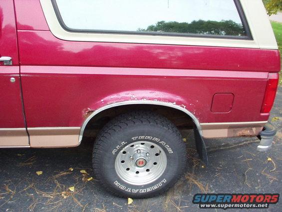 1994 Ford Bronco rear wheel well and quarter panel. Red paint with tan lower trim