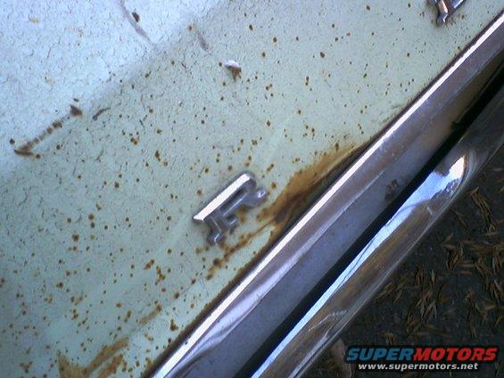 Rusted light blue car body with chrome trim and a silver R emblem