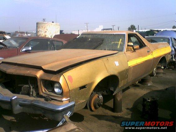Gold and brown 1973 Ford Ranchero with yellow stripe, missing wheels