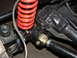 1994 Jeep YJ - Detail of vehicle suspension components, including a red coil spring and linkage, with a website watermark visible.