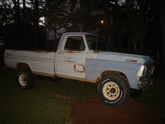 1967 Ford F-250 pickup truck, white with primer gray fender, rusty body panels, parked on grass