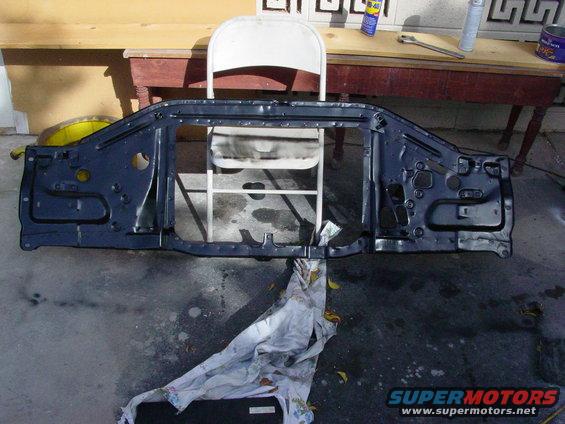 Dark blue metal radiator support assembly with holes and brackets, lying on concrete
