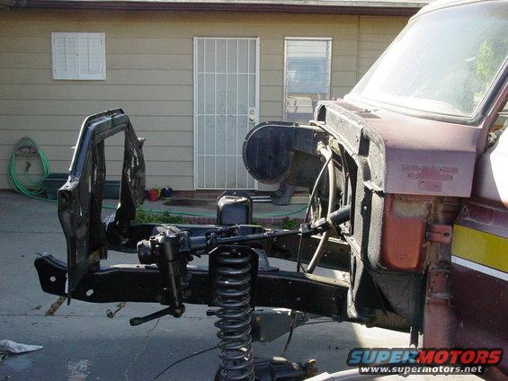 Front chassis and suspension components of a disassembled truck, with part of the cab visible