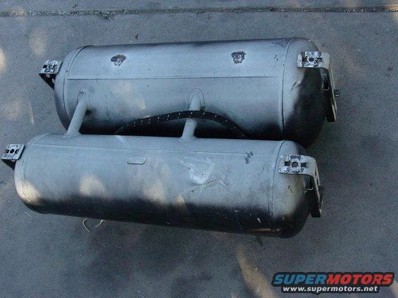 Two silver propane tanks with mounting brackets