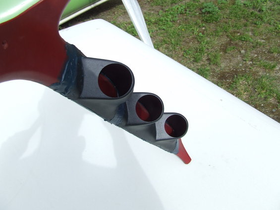 Custom gauge pod mount with three openings, painted red and black, attached to a white surface