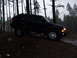 1995 Ford Bronco - A dark blue SUV navigates a muddy incline in a dense forest setting.
