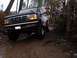 1995 Ford Bronco - A black Ford Bronco navigates a wet, wooded path with large tires.
