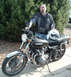 1977 Kawasaki KZ1000-A1 - A man stands next to a black 1977 Kawasaki KZ1000-A1 motorcycle with chrome accents.