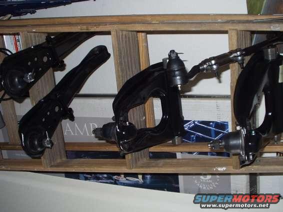Black suspension control arms and ball joints on a wooden shelf