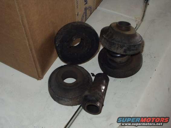 Several rubber and metal suspension components, possibly bushings and a shock absorber mount, next to a cardboard box