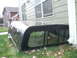 1992 Ford Ranger - A black truck bed cap with tinted windows sits on the grass next to a house.
