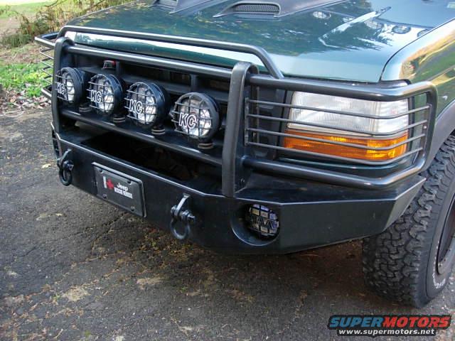 Green SUV front with brush guard, KC lights, and aftermarket bumper