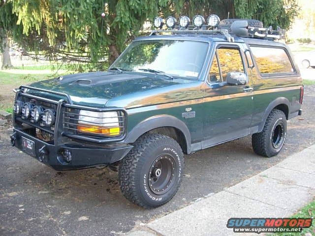 1993 Ford Bronco, dark green, with aftermarket bull bar, roof rack, and off-road tires