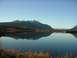 1982 Chevrolet C/K Pickup - A mountain landscape is perfectly reflected in the calm waters of a lake, with snow-capped peaks in the distance.