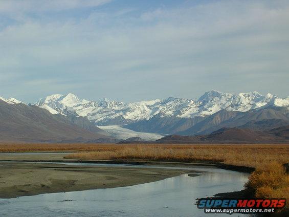 Mountain range with snow-capped peaks and a winding river in the foreground