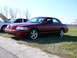 1997 Mercury Grand Marquis - A maroon sedan is parked on grass next to a white vehicle, with a number 9 visible on the windshield.