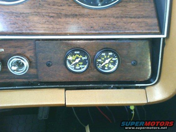 Dashboard with two aftermarket gauges and woodgrain trim