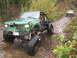 1990 Ford Bronco - A modified green off-road vehicle tackles a challenging trail with another vehicle visible in the background.