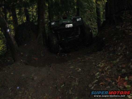 Green off-road vehicle with large tires on a muddy trail, front view
