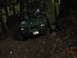 1990 Ford Bronco - A green off-road vehicle is seen on a muddy trail surrounded by trees, with its license plate visible.