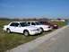 1997 Mercury Grand Marquis - Three sedans, including a white 1997 Mercury Grand Marquis, are parked in a line on a grassy area next to a paved surface.