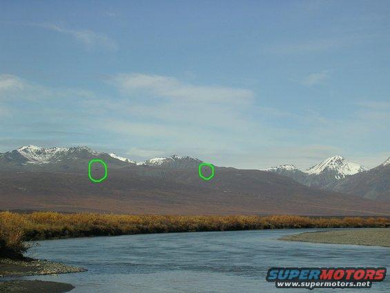 Mountains with snow-capped peaks and a winding river in the foreground under a blue sky
