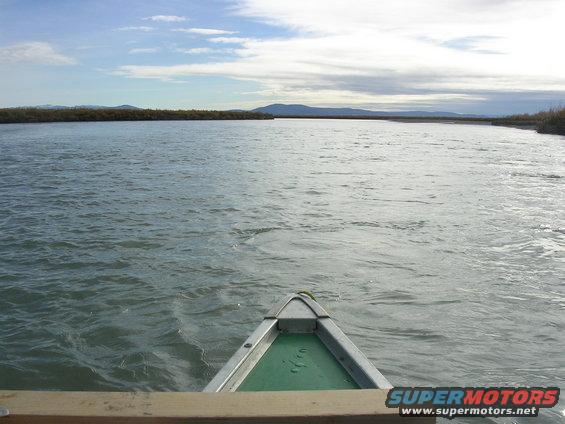 Canoe bow on a wide river under a cloudy sky