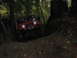 1990 Ford Bronco - A red Jeep Wrangler navigates a challenging off-road trail through a wooded area.