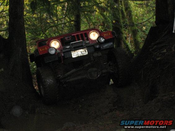 Red Jeep Wrangler climbing muddy terrain