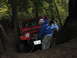 1990 Ford Bronco - A red Jeep Wrangler is stuck in the mud, with a person winching it out, while another vehicle is visible behind it.