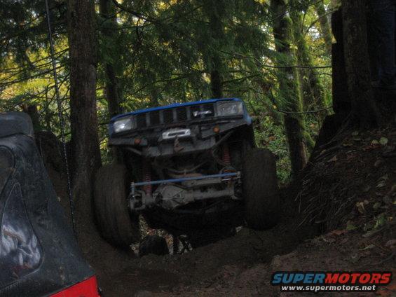 Blue off-road SUV climbing a muddy hill, front view