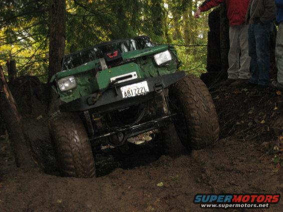 Modified off-road vehicle with large tires stuck in mud, front view. License plate A81222L visible