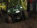 1990 Ford Bronco - Off-road vehicle navigating a muddy trail, showing its front end and large tires.