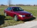 1997 Mercury Grand Marquis - A red sedan is parked on a grassy field under a clear blue sky.