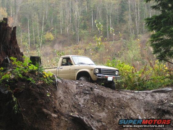 Tan pickup truck driving off-road on a muddy hill