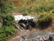 1990 Ford Bronco - White Jeep Wrangler navigating a muddy off-road trail, with another vehicle partially visible.