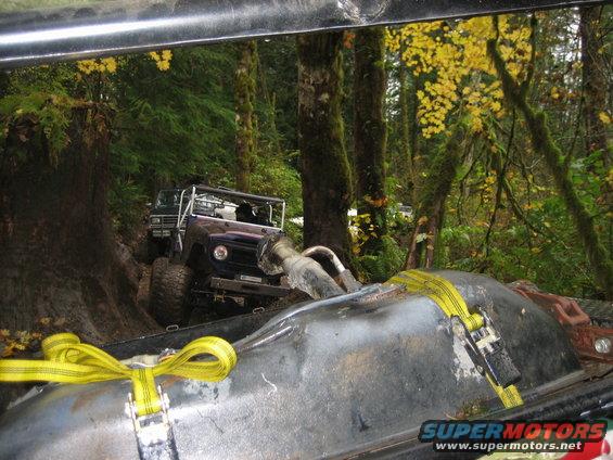 Purple off-road SUV on a muddy trail with yellow straps in foreground