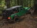 1990 Ford Bronco - A green Jeep Wrangler navigates a muddy path in a dense forest.