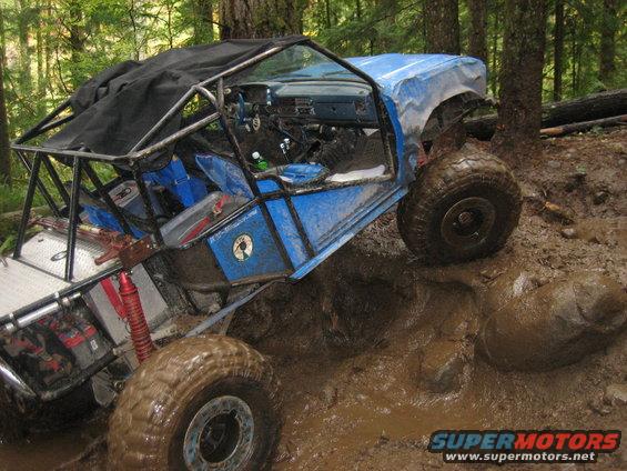Blue off-road vehicle with roll cage stuck in mud
