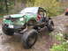 1990 Ford Bronco - A heavily modified off-road vehicle navigates a challenging rocky terrain with another vehicle visible in the background.