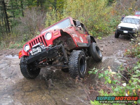 Red Jeep Wrangler on rocky trail, white Jeep Cherokee behind it