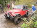 1990 Ford Bronco - A red Jeep Wrangler tackles a challenging off-road course, demonstrating its capabilities.