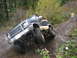 1990 Ford Bronco - A modified SUV navigates a challenging off-road course with a person watching in the background.
